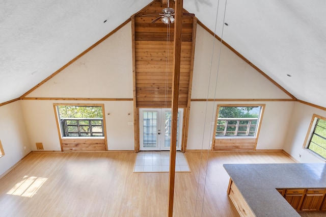 unfurnished living room featuring high vaulted ceiling, plenty of natural light, light hardwood / wood-style floors, and ceiling fan