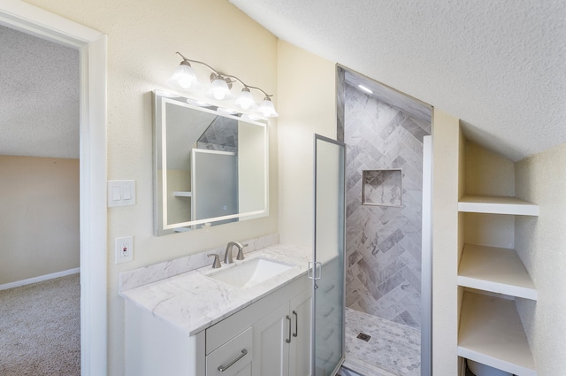 bathroom featuring tiled shower, vanity, and a textured ceiling