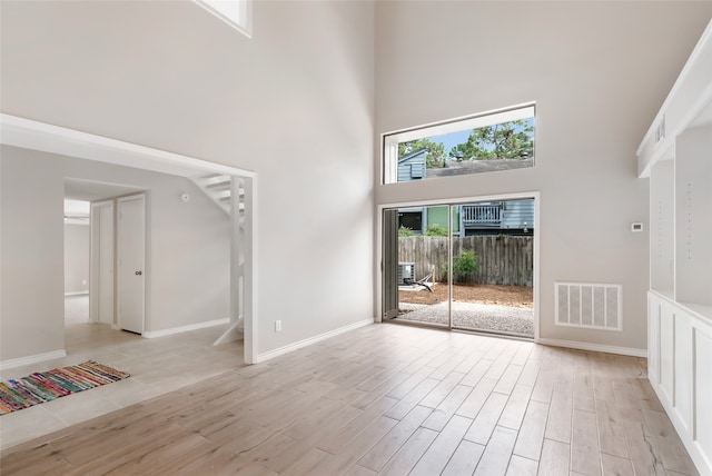 unfurnished living room featuring a towering ceiling and light hardwood / wood-style floors