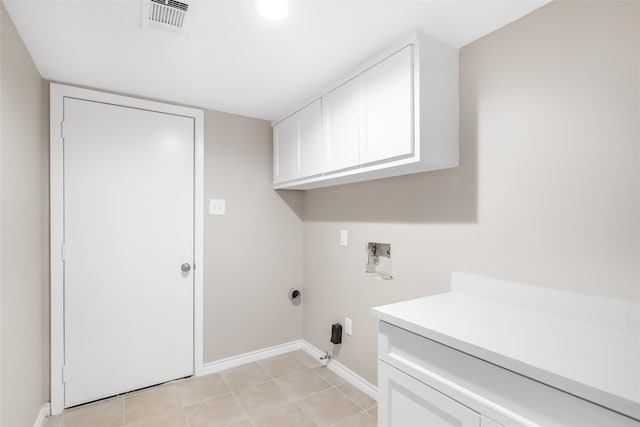 clothes washing area featuring washer hookup, cabinets, and light tile patterned floors