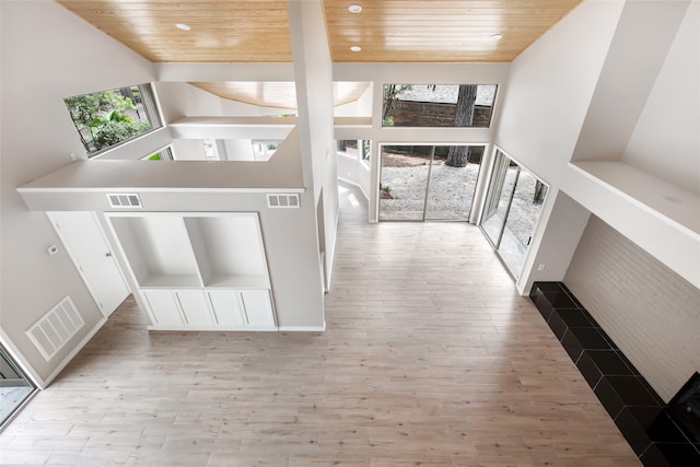 interior space featuring light wood-type flooring, wood ceiling, and a towering ceiling