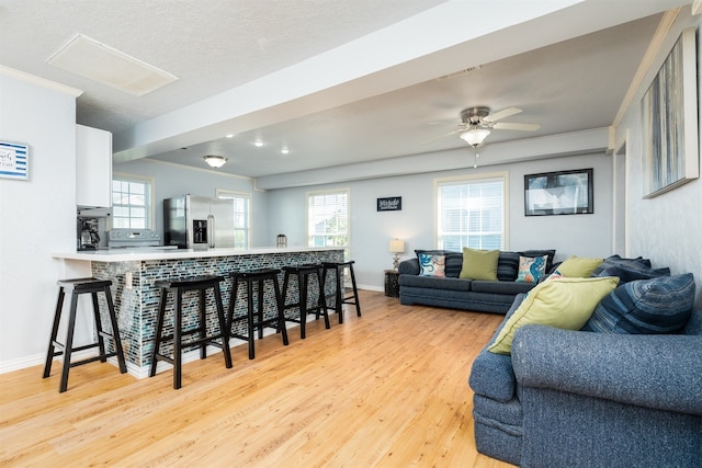 living room featuring plenty of natural light, light wood-style flooring, and baseboards