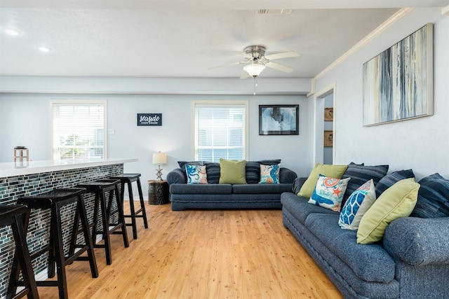 living room featuring plenty of natural light, ceiling fan, ornamental molding, and light hardwood / wood-style flooring