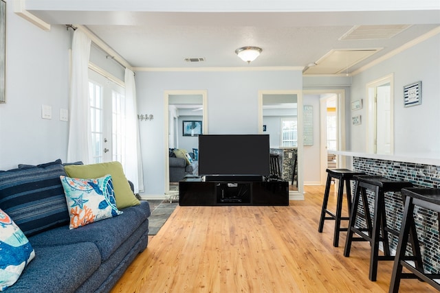 living room featuring wood-type flooring, ornamental molding, and a healthy amount of sunlight