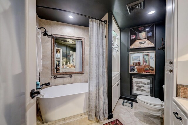 bathroom with a tub, tile walls, toilet, vanity, and tile patterned flooring