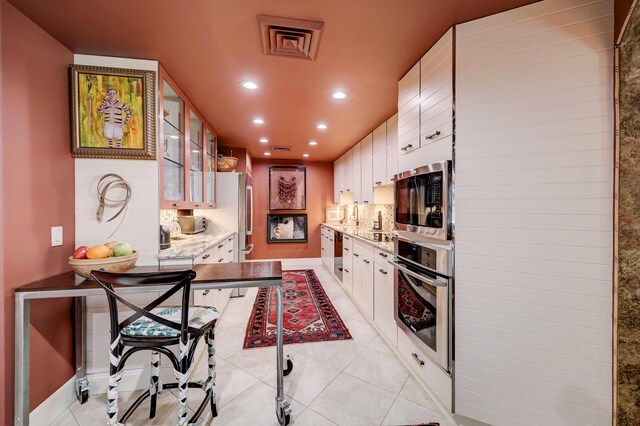 kitchen featuring light tile patterned flooring, white cabinets, and stainless steel appliances