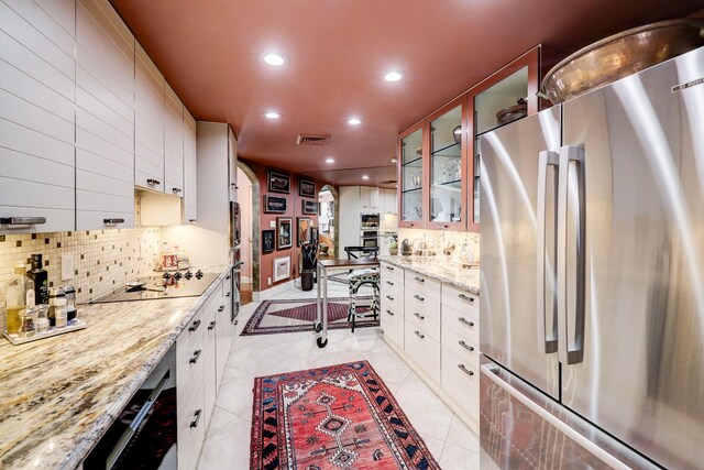 kitchen featuring white cabinetry, light stone counters, appliances with stainless steel finishes, and light tile patterned floors