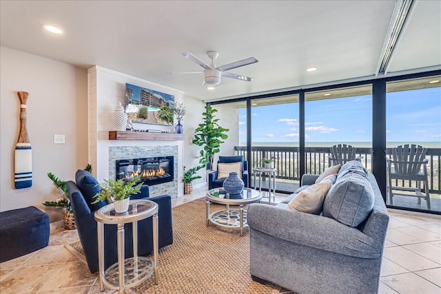 living room with a large fireplace, ceiling fan, and expansive windows