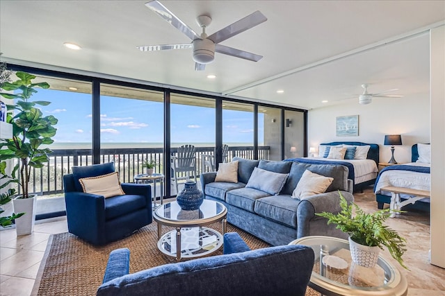 living room featuring a water view, ceiling fan, expansive windows, and tile patterned floors