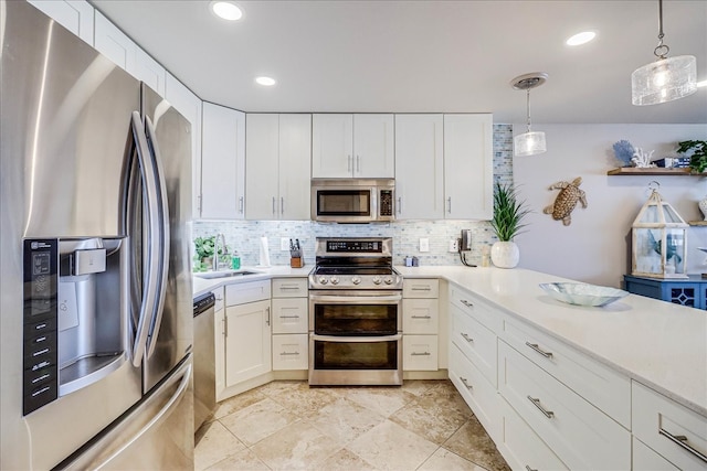 kitchen featuring tasteful backsplash, sink, hanging light fixtures, appliances with stainless steel finishes, and white cabinets