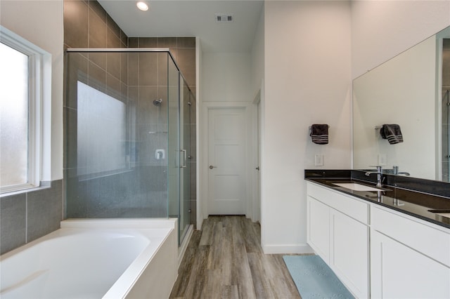 bathroom featuring a healthy amount of sunlight, wood-type flooring, shower with separate bathtub, and vanity