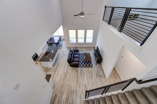 living room featuring ceiling fan, wood-type flooring, and a high ceiling