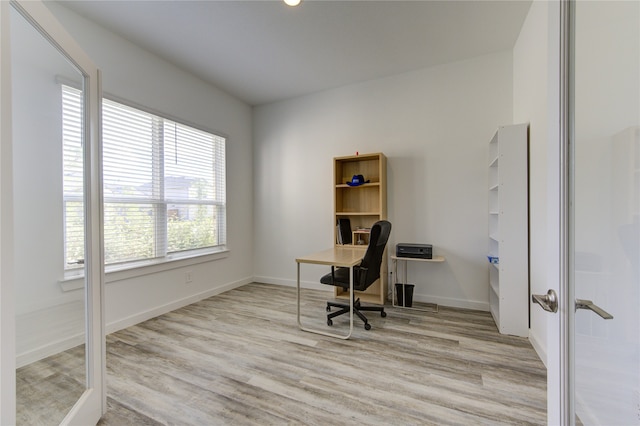 office with french doors and light hardwood / wood-style floors