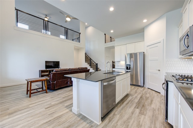 kitchen with white cabinets, stainless steel appliances, a center island with sink, and sink