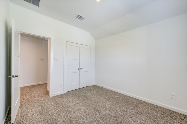 unfurnished bedroom with a closet, light colored carpet, and vaulted ceiling