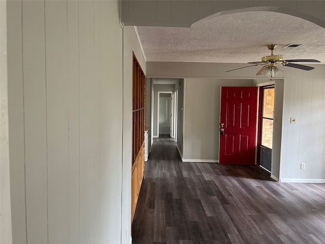 foyer with a textured ceiling, wooden walls, ceiling fan, and dark hardwood / wood-style floors