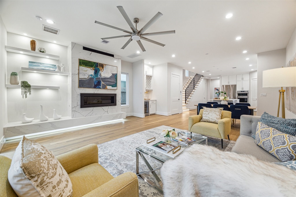 living room featuring a premium fireplace, ceiling fan, and light hardwood / wood-style floors