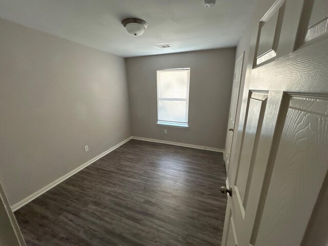 unfurnished room with dark wood-type flooring