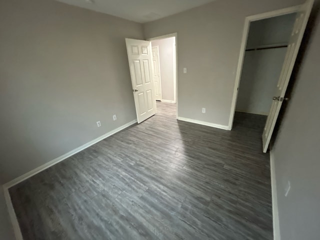 unfurnished bedroom with dark hardwood / wood-style flooring and a closet