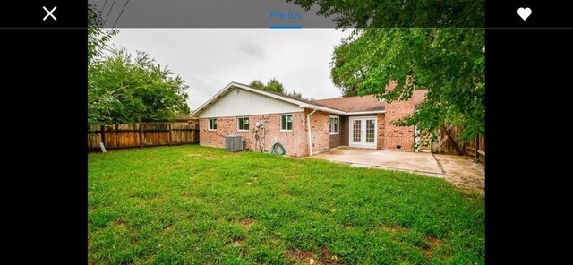 rear view of property with central AC unit, a patio area, and a lawn