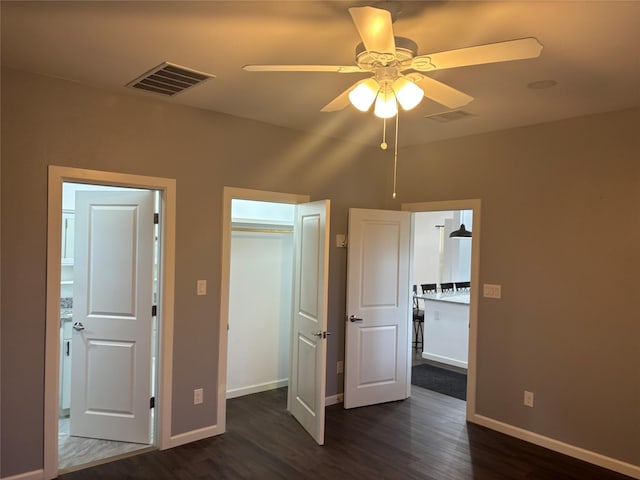 unfurnished bedroom with ceiling fan, dark wood-type flooring, and a closet