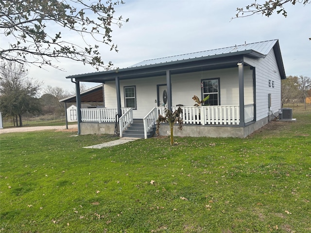 view of front of home with a porch, a front yard, and central AC