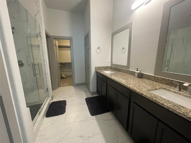 full bathroom with a walk in closet, marble finish floor, a sink, a marble finish shower, and double vanity