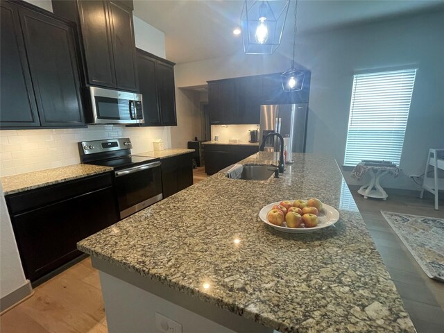 kitchen featuring tasteful backsplash, a center island with sink, appliances with stainless steel finishes, and dark stone countertops