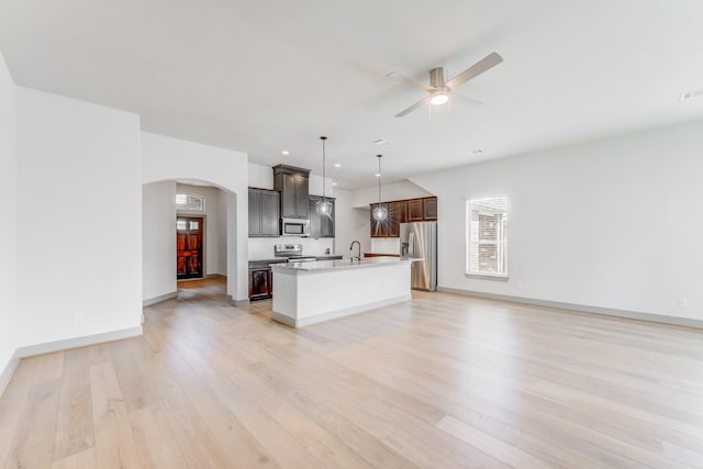 11913 Mockingbird Ln, Montgomery, TX 77356 - kitchen featuring stainless steel appliances, arched walkways, open floor plan, light wood-style floors, and a ceiling fan