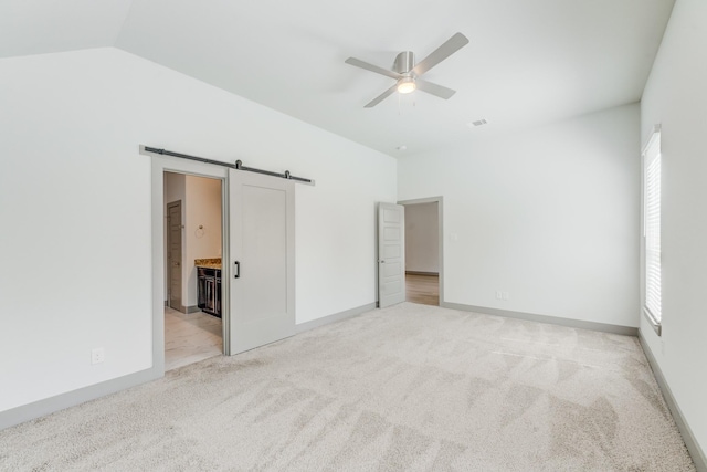11913 Mockingbird Ln, Montgomery, TX 77356 - unfurnished bedroom with a barn door, light colored carpet, lofted ceiling, baseboards, and connected bathroom