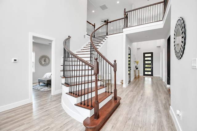 foyer entrance with a towering ceiling and light hardwood / wood-style floors