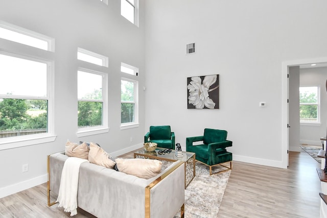 living room with a towering ceiling and light wood-type flooring