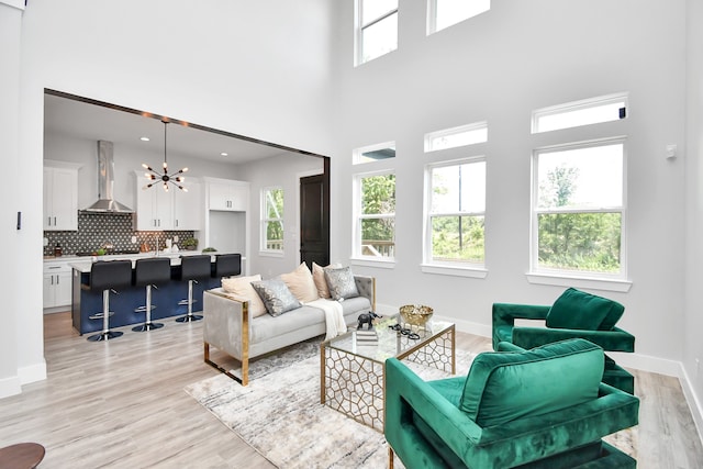 living room featuring light hardwood / wood-style floors, a chandelier, and a high ceiling