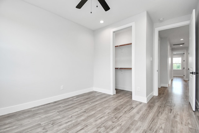 unfurnished bedroom featuring ceiling fan, a closet, and light wood-type flooring