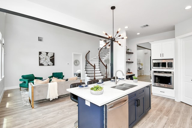 kitchen with sink, white cabinetry, blue cabinets, a center island with sink, and stainless steel appliances