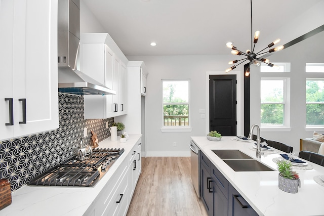 kitchen with light stone countertops, white cabinetry, appliances with stainless steel finishes, and wall chimney exhaust hood