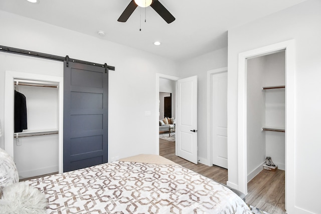 bedroom with ceiling fan, hardwood / wood-style flooring, a closet, and a barn door