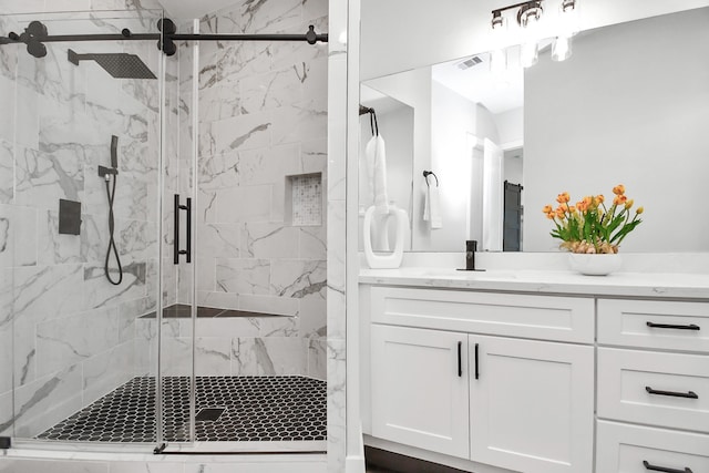 bathroom featuring a shower with door and vanity