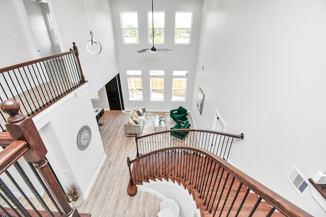 stairs featuring ceiling fan, a high ceiling, and hardwood / wood-style floors