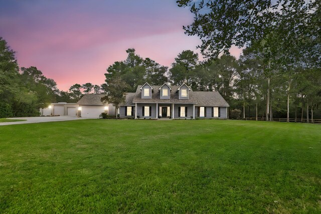 cape cod-style house with a garage and a lawn