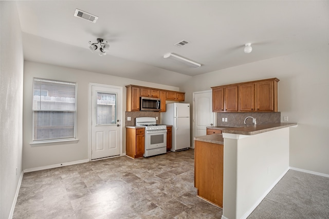 kitchen with white appliances, kitchen peninsula, and backsplash