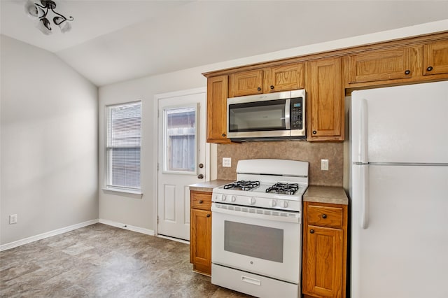 kitchen featuring vaulted ceiling, white appliances, and decorative backsplash