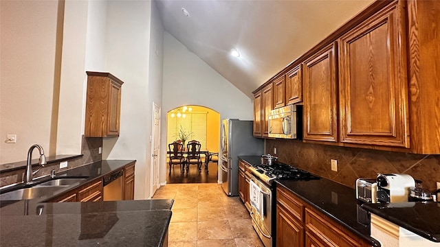 kitchen featuring dark stone counters, high vaulted ceiling, backsplash, sink, and appliances with stainless steel finishes