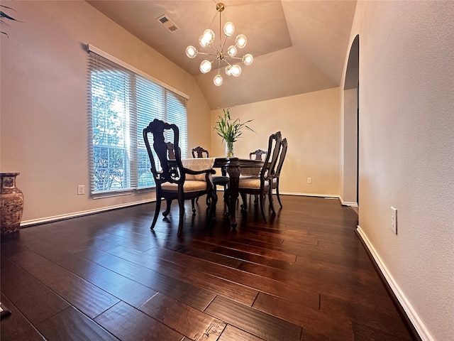 dining area with a raised ceiling, dark hardwood / wood-style floors, and an inviting chandelier