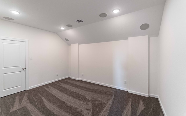 spare room featuring lofted ceiling and dark carpet