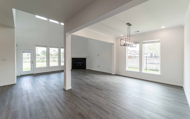 unfurnished living room featuring crown molding, dark hardwood / wood-style floors, and a wealth of natural light