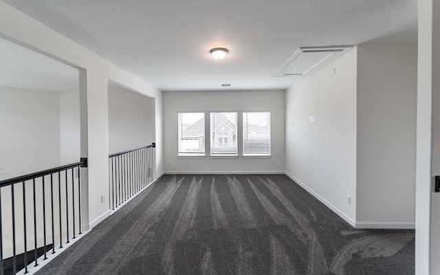 spare room with dark carpet and a textured ceiling