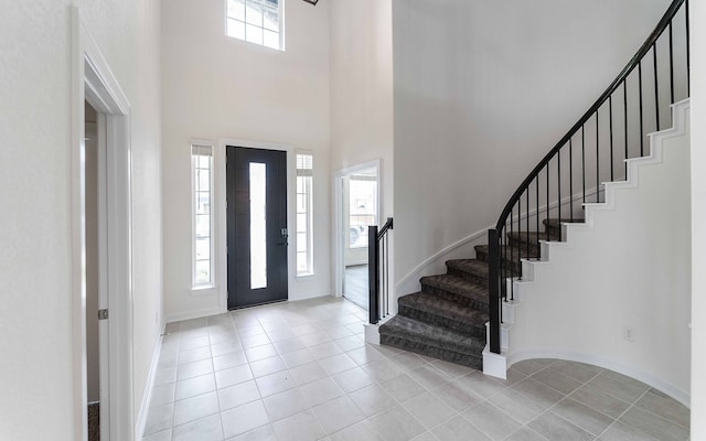 foyer entrance with a towering ceiling, light tile patterned floors, and a wealth of natural light