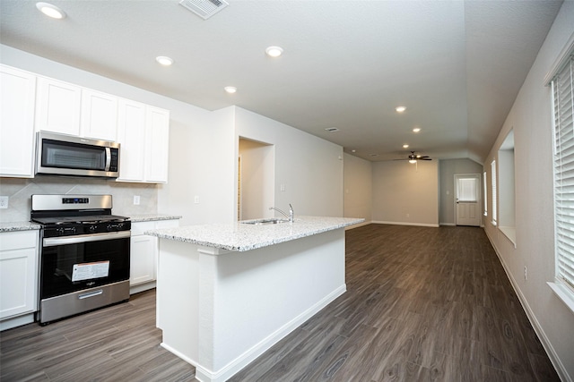 kitchen with decorative backsplash, appliances with stainless steel finishes, ceiling fan, a center island with sink, and white cabinetry