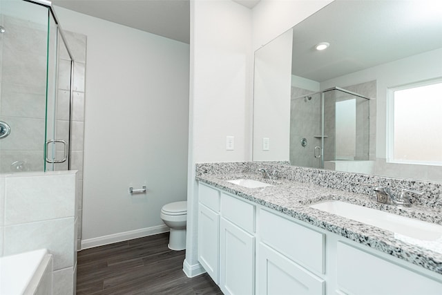 bathroom with wood-type flooring, vanity, toilet, and a shower with door